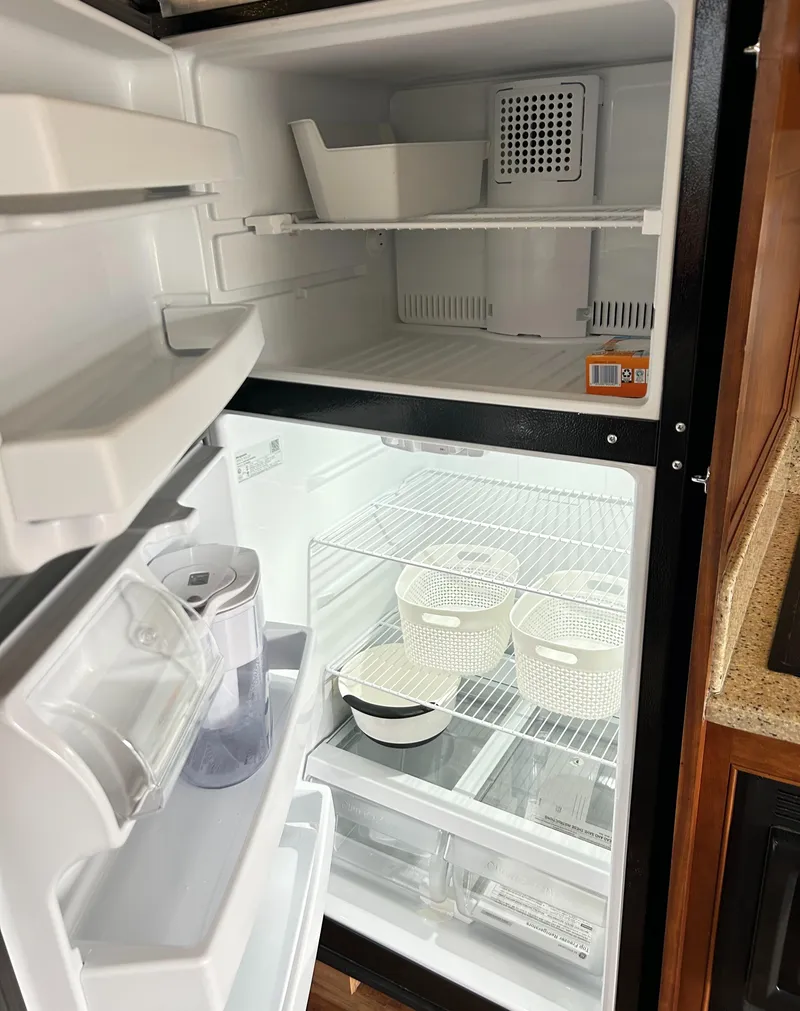 Slide: The Image of Open refrigerator inside 2004 Cruisers Yachts 5000 Sedan Sport, showing organized shelves and containers. - 41