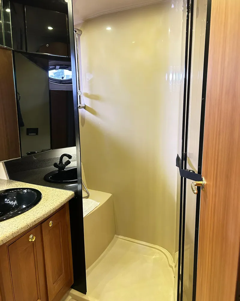 Slide: The Image of 2004 Cruisers Yachts 5000 Sedan Sport bathroom with shower, sink, and wooden cabinetry. - 49