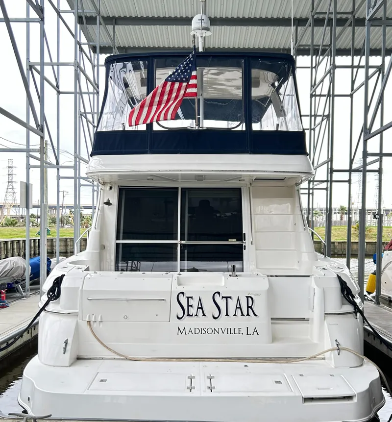 Slide: The Image of 2004 Cruisers Yachts 5000 Sedan Sport docked, rear view with American flag. - 5