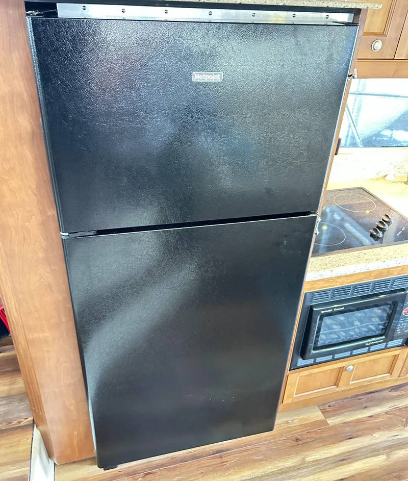 Slide: The Image of Black refrigerator in a 2004 Cruisers Yachts 5000 Sedan Sport kitchen area. - 27