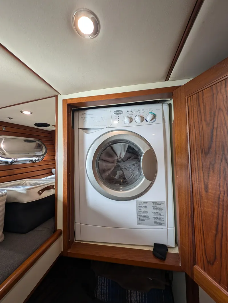 Slide: The Image of Laundry area inside a 2002 Nordhavn Trawler, featuring a built-in washing machine. - 32
