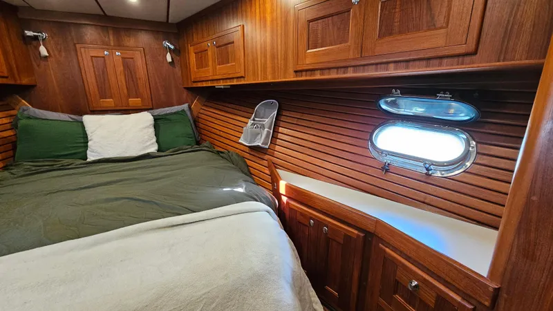 Slide: The Image of Cozy 2002 Nordhavn Trawler cabin with wood paneling, bed, and porthole window. - 36