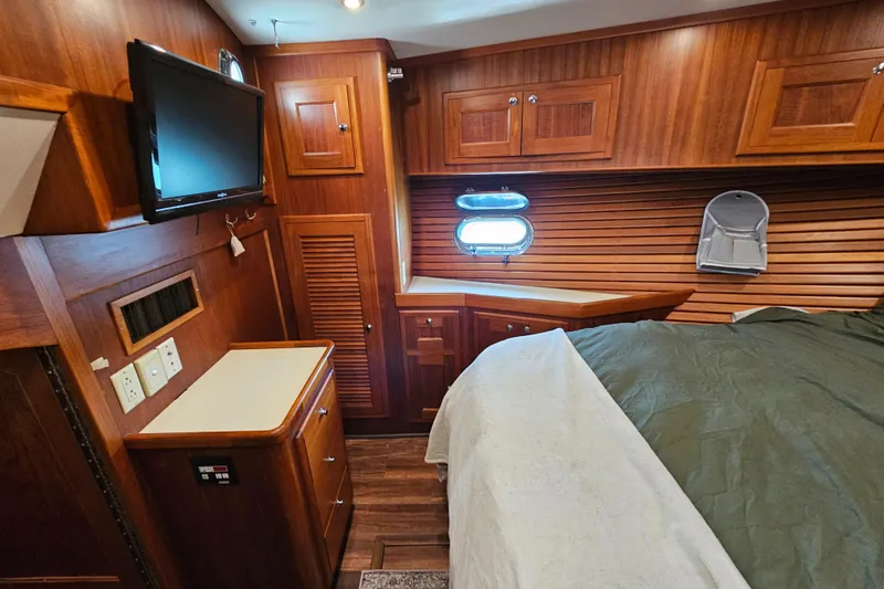 Slide: The Image of Luxurious 2002 Nordhavn Trawler cabin with wood paneling, bed, and TV. - 37