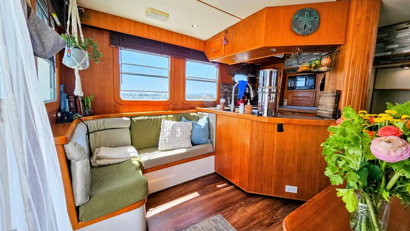 Slide: The Image of Cozy 2002 Nordhavn Trawler interior with wooden decor, seating area, and vibrant flowers. - 4
