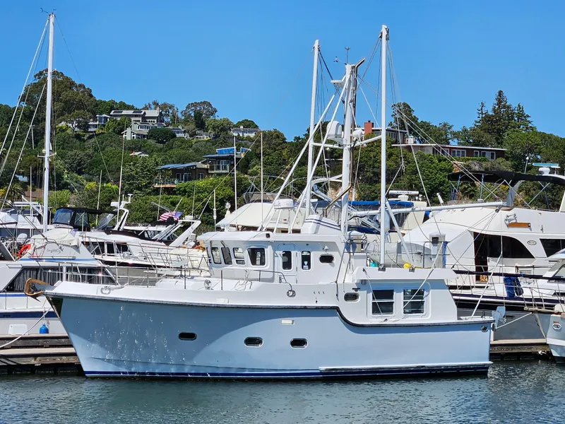 Slide: The Image of 2002 Nordhavn Trawler docked at marina, surrounded by other boats, with hillside homes in background. - 43