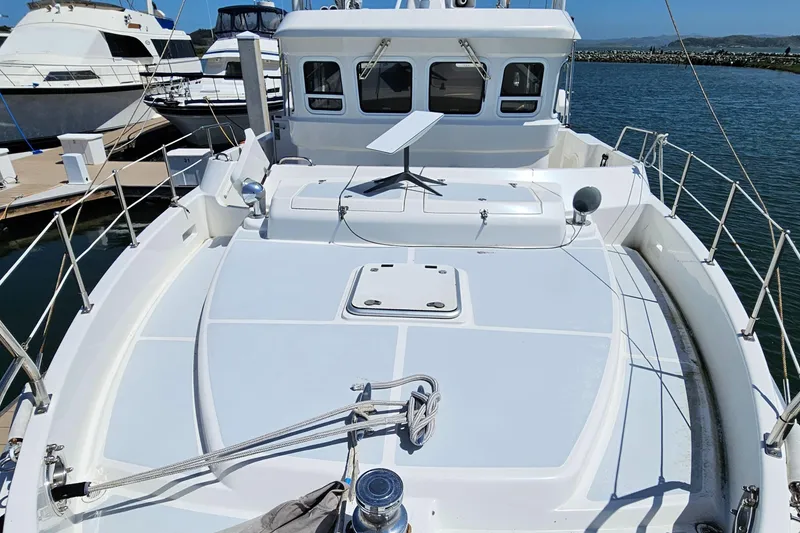 Slide: The Image of 2002 Nordhavn Trawler boat deck with railing, docked in marina under clear sky. - 44