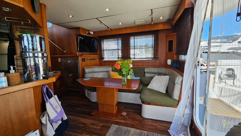 Slide: The Image of Luxurious 2002 Nordhavn Trawler interior with cozy seating, wooden accents, and a vibrant floral centerpiece. - 7