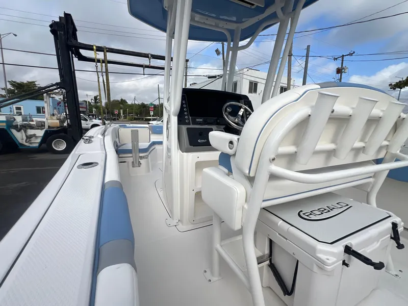Slide: The Image of 2025 Robalo 232 Explorer boat interior with helm and seating, docked outdoors. - 10