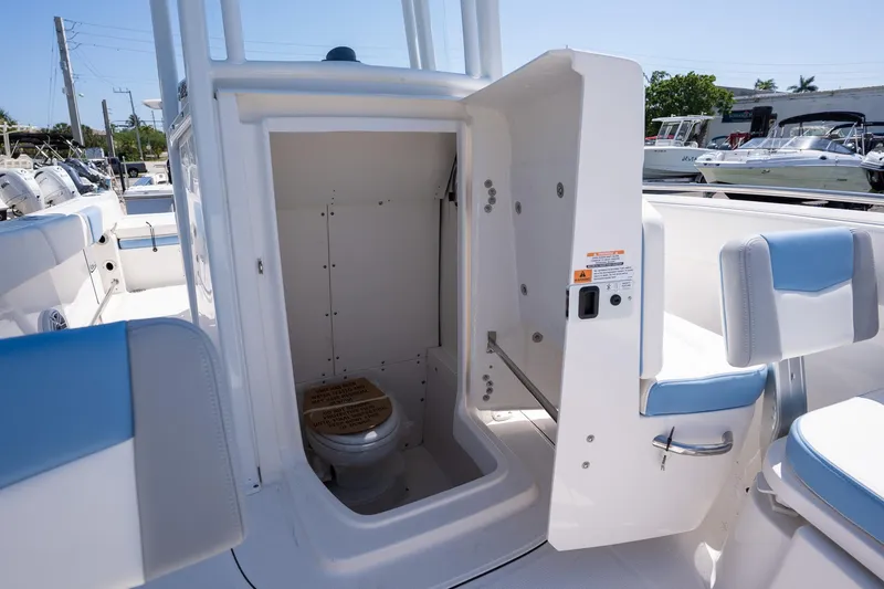 Slide: The Image of 2025 Robalo 232 Explorer boat interior with open compartment showing a compact marine toilet. - 14