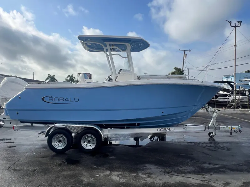 Slide: The Image of 2025 Robalo 232 Explorer boat on trailer, blue hull, parked outdoors. - 5