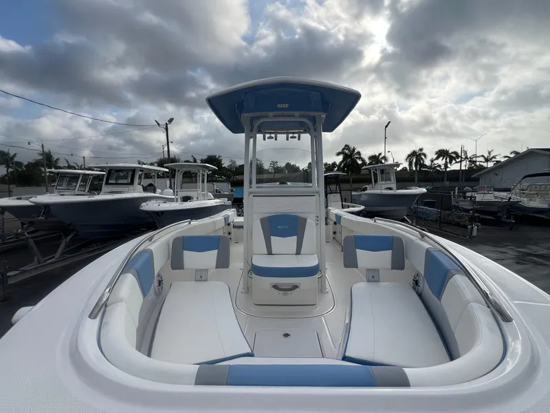 Slide: The Image of 2025 Robalo 232 Explorer boat with blue and white seating, docked under cloudy skies. - 6