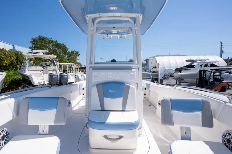 Slide: The Image of 2025 Robalo 232 Explorer boat interior with blue and white seating, docked outdoors. - 7