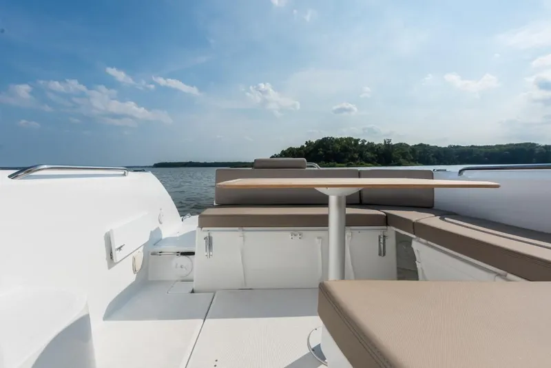 Slide: The Image of 2025 Beneteau Antares 7 boat deck with seating, table, and scenic water view. - 13