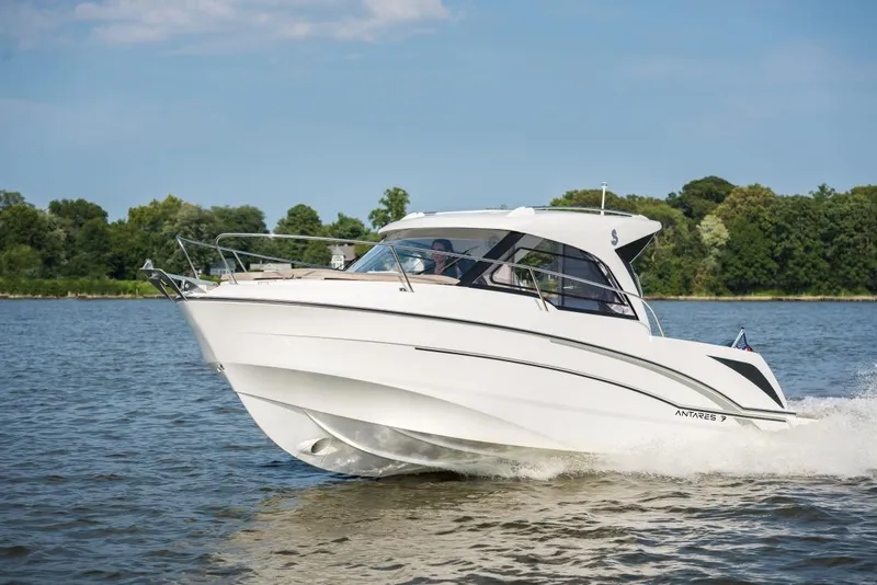 Slide: The Image of 2025 Beneteau Antares 7 cruising on a serene lake with lush green trees. - 2