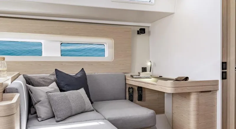 Slide: The Image of Interior of 2025 Beneteau Oceanis Yacht 54, featuring modern seating and desk area. - 19