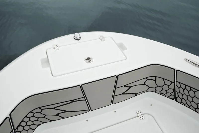 Slide: The Image of 2025 Wellcraft 202 Fisherman boat deck with storage compartment, sleek design, and water backdrop. - 11