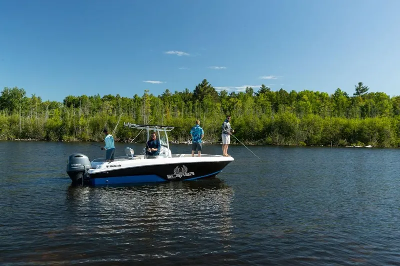 Slide: The Image of 2025 Wellcraft 202 Fisherman boat on a lake with people fishing, surrounded by trees. - 2