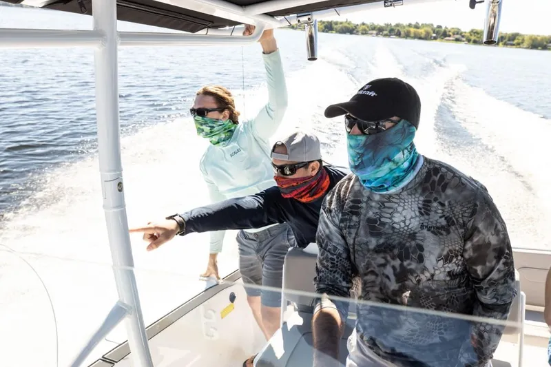 Slide: The Image of Three people on a 2025 Wellcraft 202 Fisherman boat, wearing face coverings, enjoying a sunny day. - 6