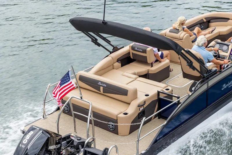 Slide: The Image of 2025 Barletta Cabrio 24UC pontoon boat cruising on a lake with passengers. - 14