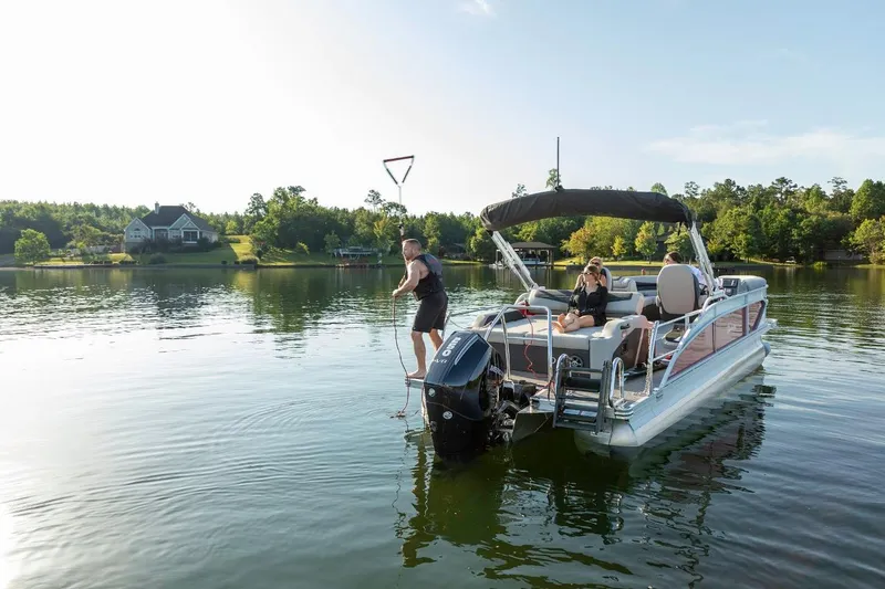 Slide: The Image of 2025 Barletta Cabrio 24UC pontoon boat on a serene lake with passengers enjoying the view. - 5