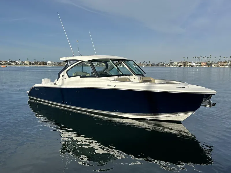 Slide: The Image of 2021 Pursuit DC 326 Dual Console boat on calm water, clear sky background. - 1