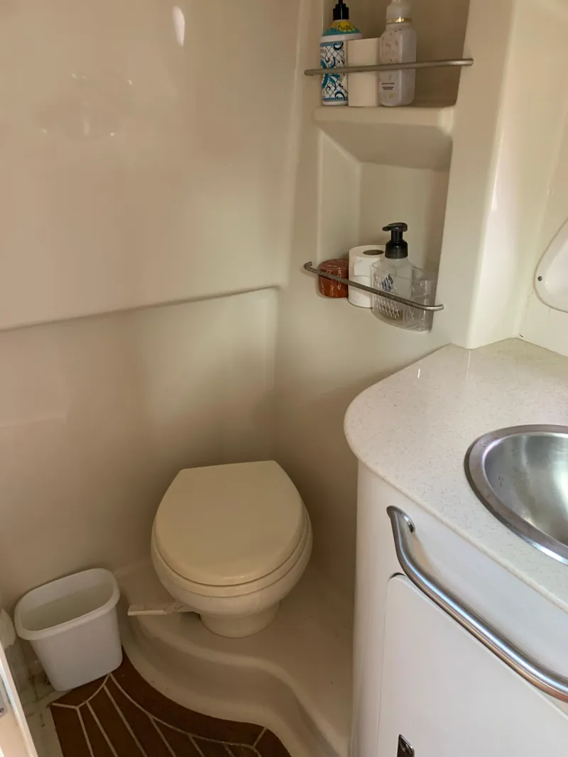Slide: The Image of 2011 Sea Ray 330 Sundancer bathroom with toilet, sink, and storage shelves. - 12