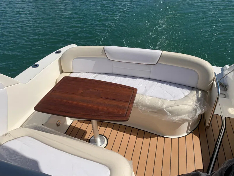Slide: The Image of 2011 Sea Ray 330 Sundancer boat with cushioned seating and wooden table on deck. - 2
