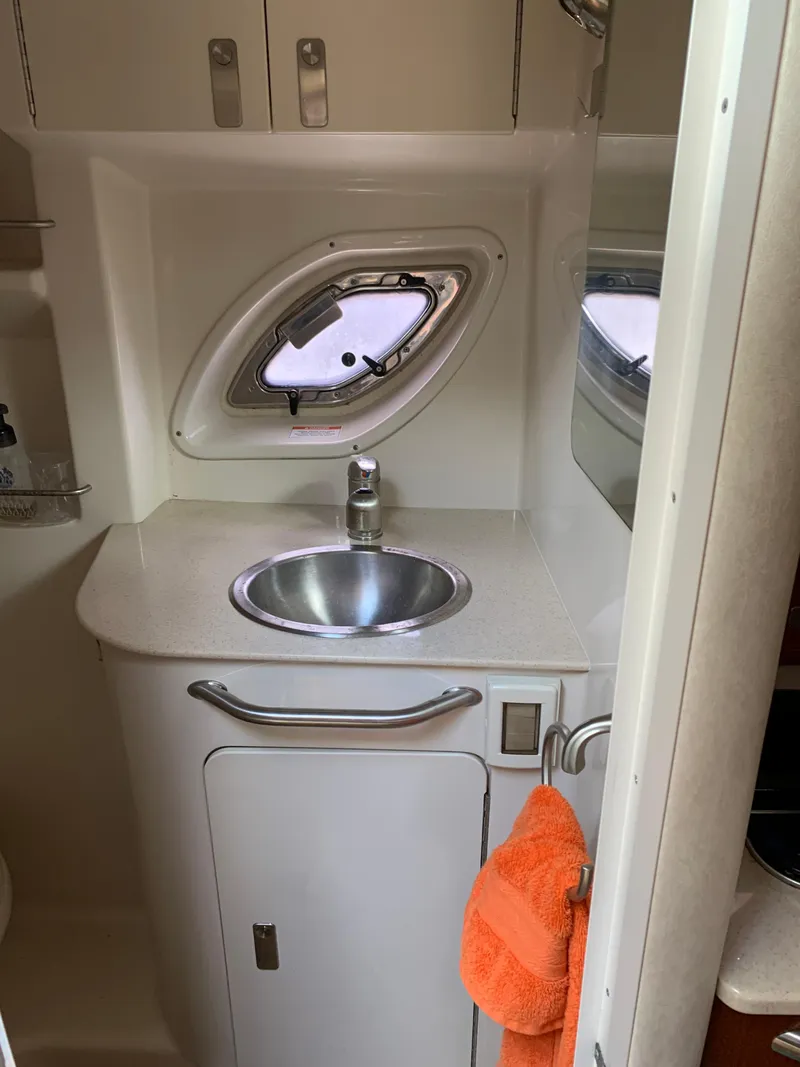 Slide: The Image of 2011 Sea Ray 330 Sundancer bathroom with sink, porthole, and orange towel. - 23