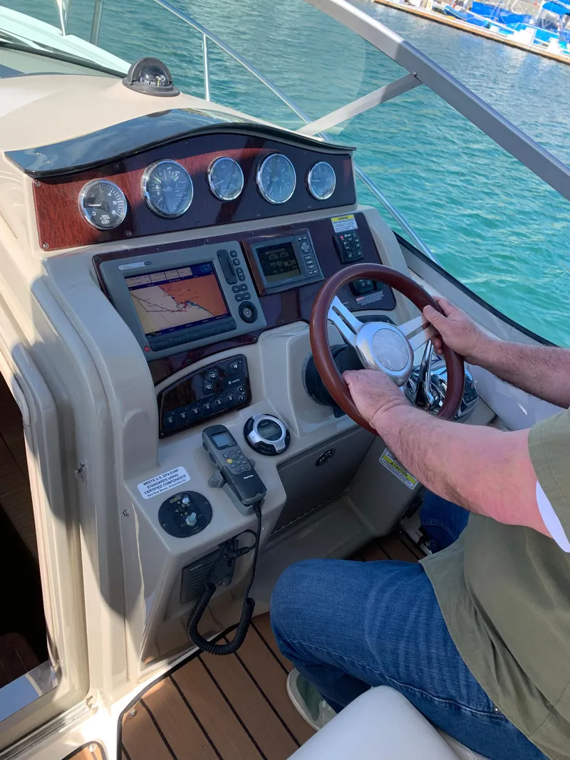 Slide: The Image of Person steering 2011 Sea Ray 330 Sundancer yacht, dashboard with navigation instruments visible. - 3