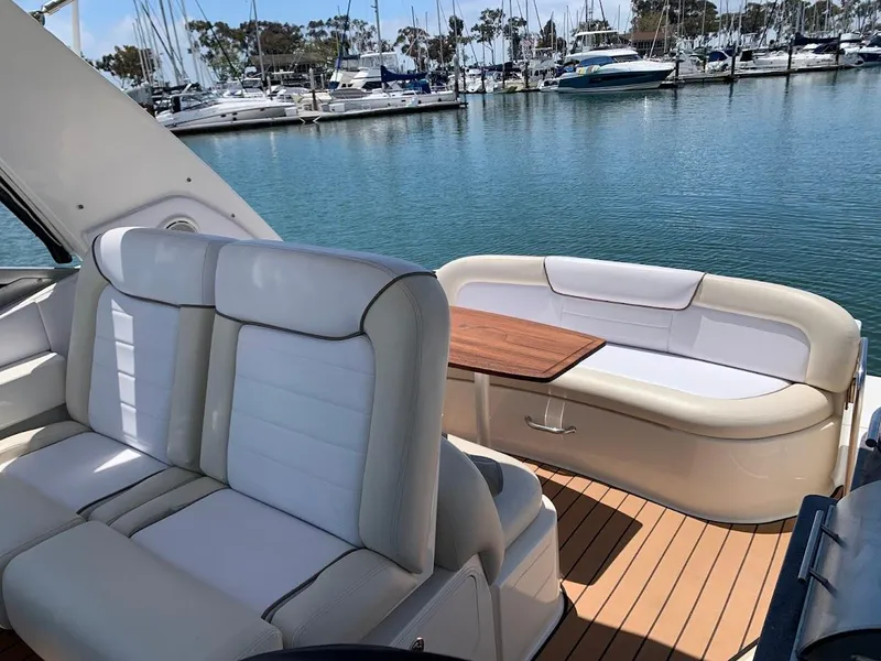 Slide: The Image of 2011 Sea Ray 330 Sundancer yacht interior with white seating and wooden table, docked at marina. - 32