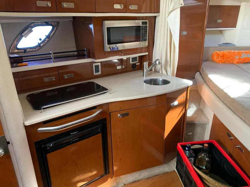 Slide: The Image of 2011 Sea Ray 330 Sundancer interior kitchen with microwave, sink, and stove. - 6