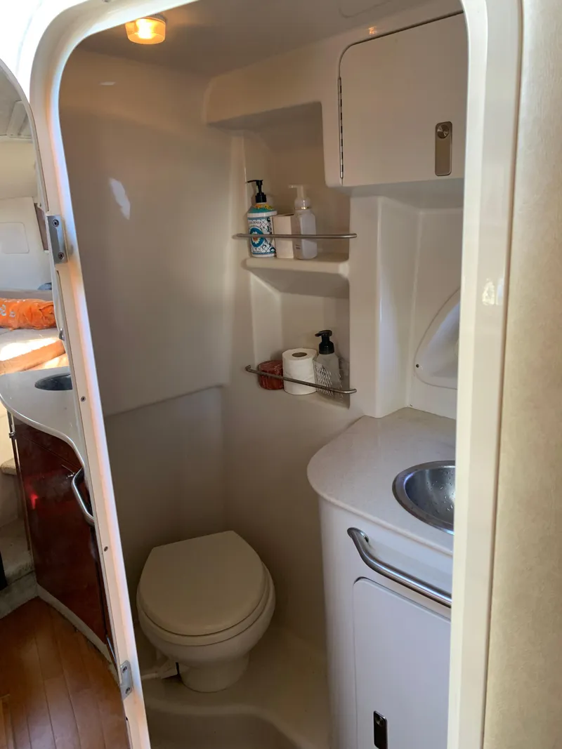 Slide: The Image of 2011 Sea Ray 330 Sundancer bathroom with toilet, sink, and storage shelves. - 7