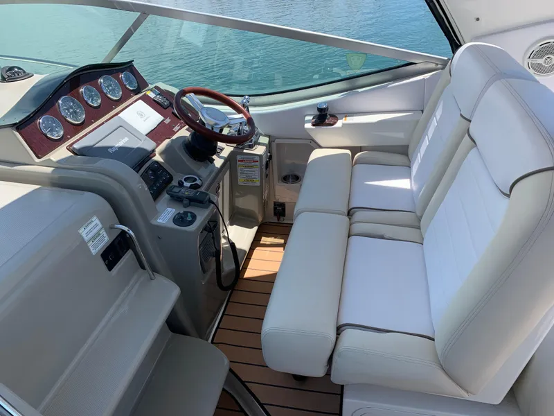 Slide: The Image of 2011 Sea Ray 330 Sundancer helm with leather seating and wooden dashboard, overlooking water. - 9