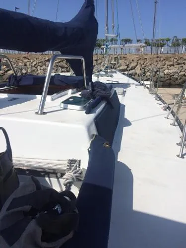 Slide: The Image of 1993 Columbia Cutter sailboat deck with blue covers, docked near a stone wall. - 15