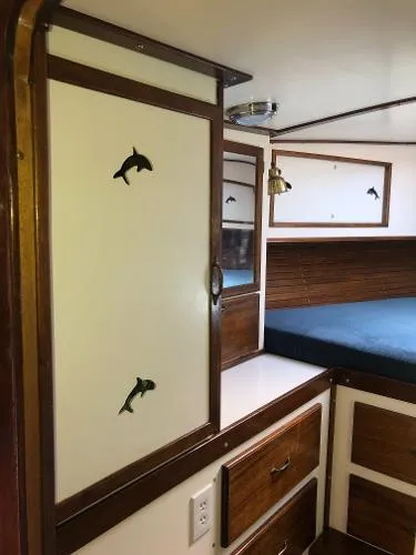 Slide: The Image of Interior of a 1993 Columbia Cutter boat with dolphin-themed decor and wooden cabinetry. - 29