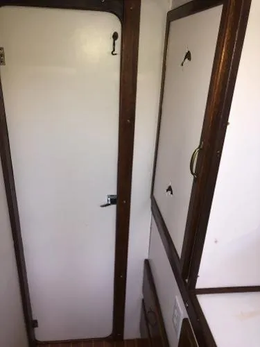 Slide: The Image of Interior of a 1993 Columbia Cutter boat, featuring a wooden-framed door and cabinets. - 38