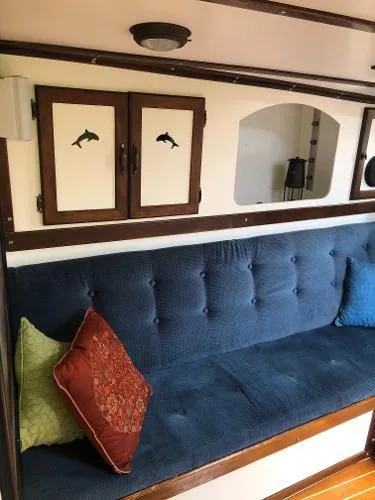 Slide: The Image of 1993 Columbia Cutter interior with blue cushioned seating, decorative pillows, and dolphin-themed cabinet doors. - 39