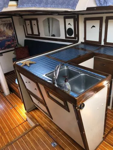 Slide: The Image of 1993 Columbia Cutter yacht interior with wooden flooring, blue-tiled kitchen, and nautical decor. - 48
