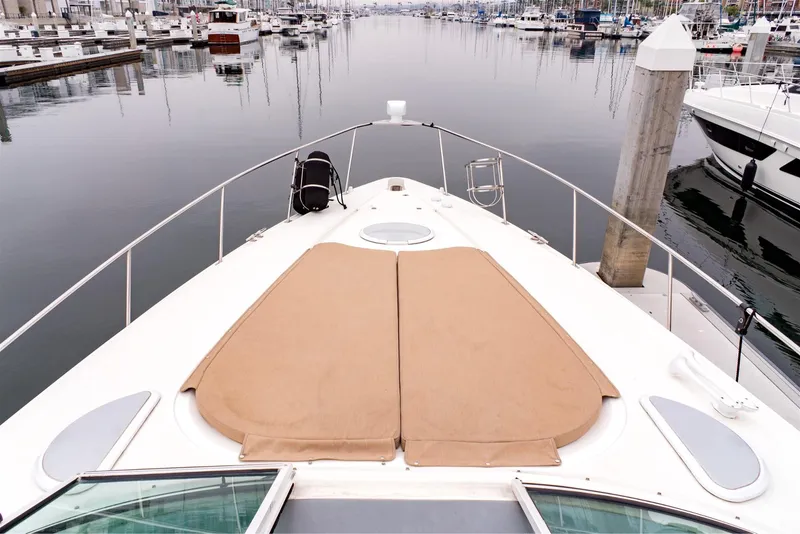Slide: The Image of 2005 Cruisers Yachts 370 Express bow view in marina, featuring sun pads and calm waters. - 13