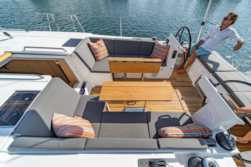 Slide: The Image of 2024 Bavaria C45 yacht deck with seating, tables, and striped cushions, overlooking the water. - 15