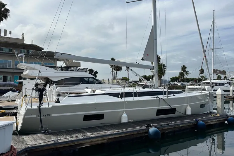 Slide: The Image of 2024 Bavaria C45 yacht docked at marina, with sail and palm trees in background. - 2