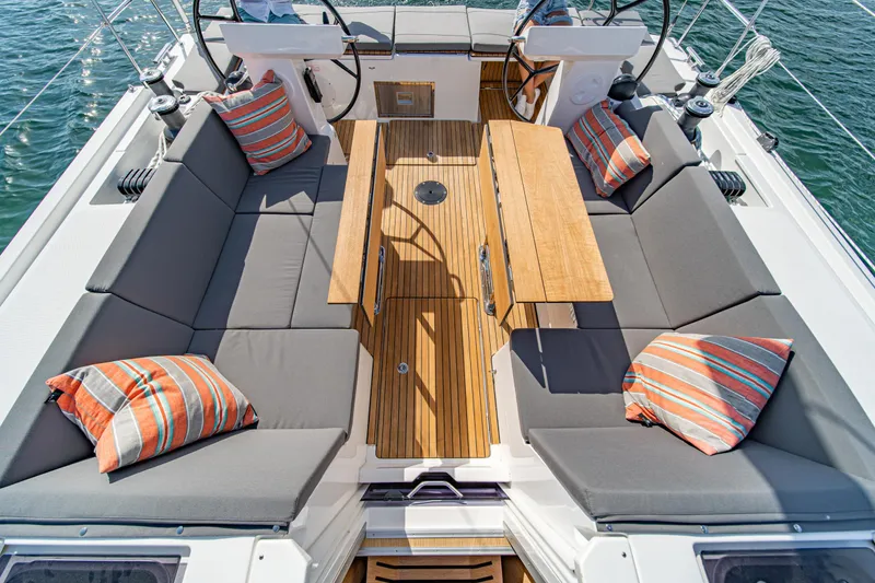 Slide: The Image of 2024 Bavaria C45 yacht cockpit with cushioned seating and striped pillows. - 30