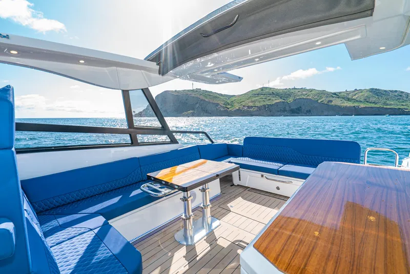 Slide: The Image of 2024 Bavaria Vida 33 yacht interior with blue seating and wooden table, ocean view. - 28