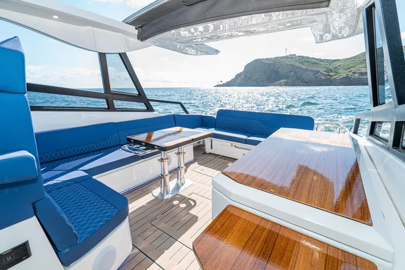 Slide: The Image of 2024 Bavaria Vida 33 yacht interior with blue seating and wooden table, ocean view. - 29