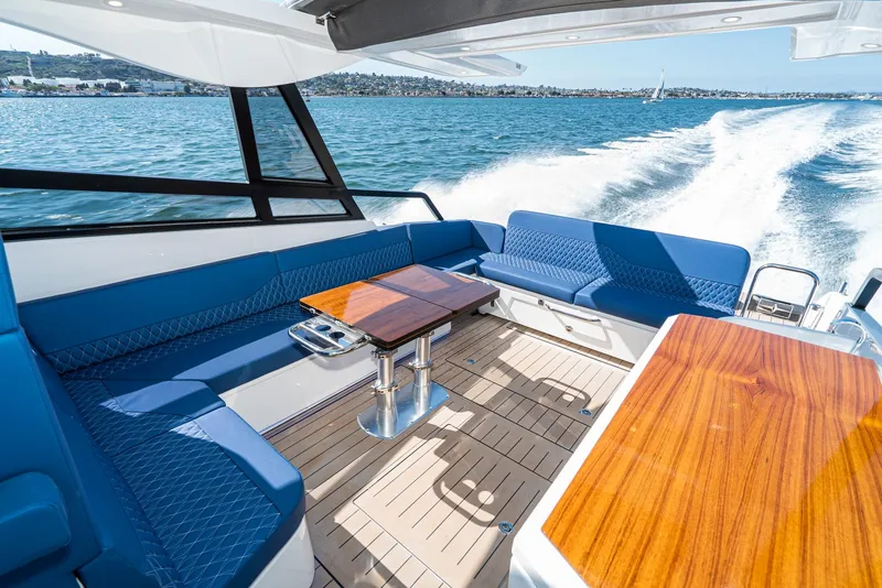 Slide: The Image of 2024 Bavaria Vida 33 yacht interior with blue seating and wooden tables on open water. - 30