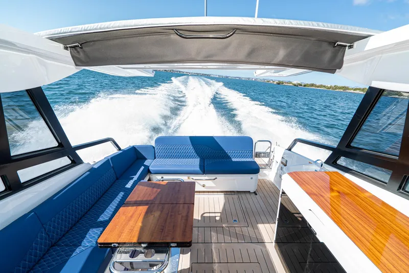 Slide: The Image of 2024 Bavaria Vida 33 yacht interior with blue seating and wooden tables on open water. - 31