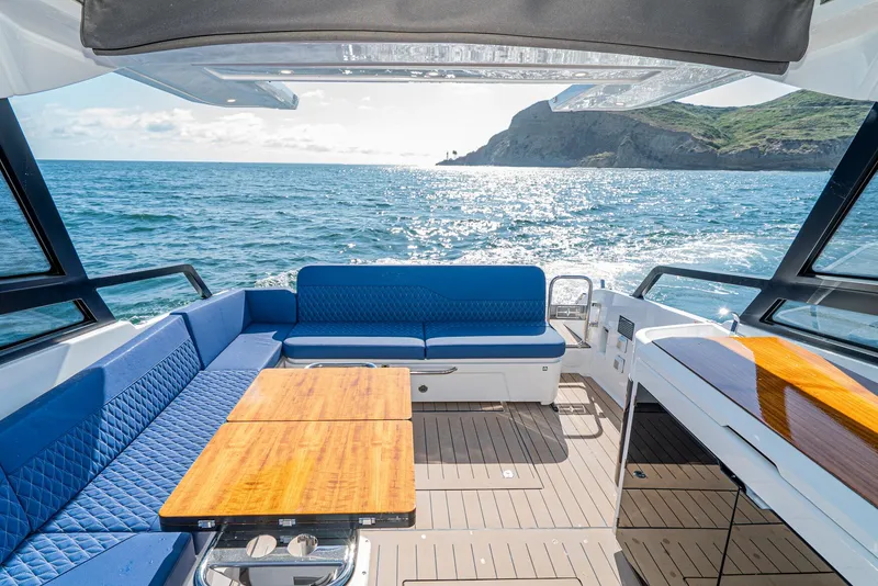 Slide: The Image of 2024 Bavaria Vida 33 yacht interior with blue seating, wooden tables, and ocean view. - 32