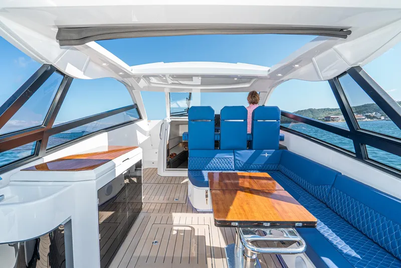 Slide: The Image of 2024 Bavaria Vida 33 yacht interior with blue seating and wooden tables, cruising on open water. - 33