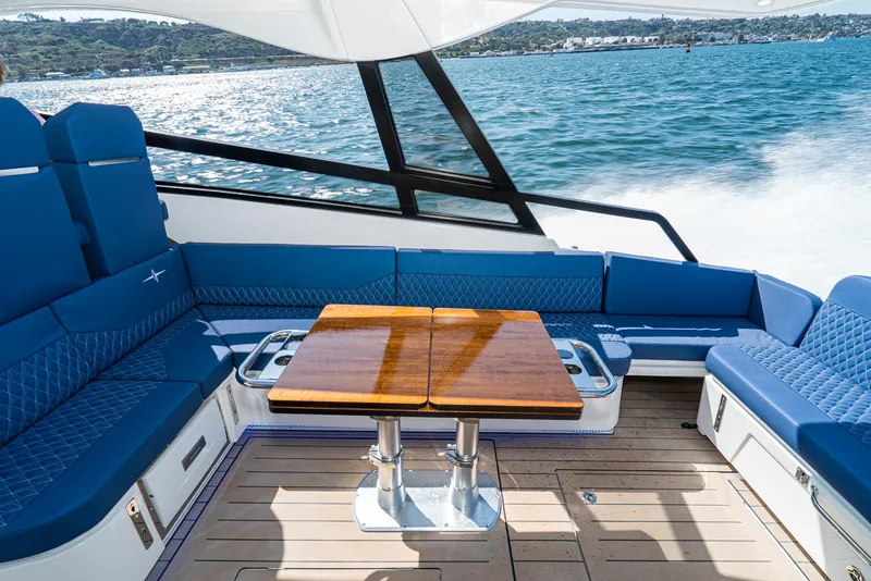 Slide: The Image of 2024 Bavaria Vida 33 yacht interior with blue seating and wooden table on open water. - 36