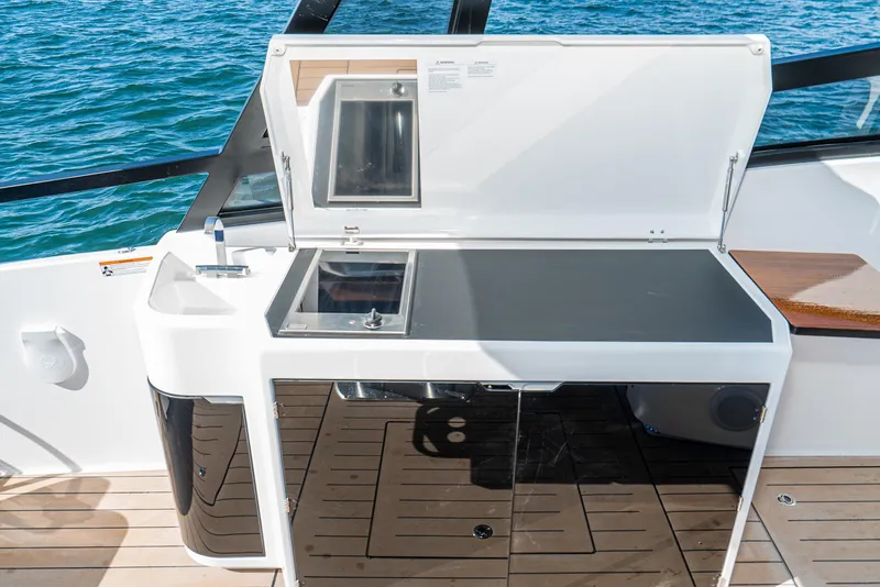 Slide: The Image of 2024 Bavaria Vida 33 yacht kitchenette with sink and stove, set against ocean backdrop. - 39